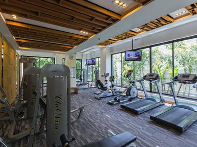 Moderner Fitnessraum mit Laufbändern, Fahrrädern und großen Fenstern mit Blick ins Grüne.