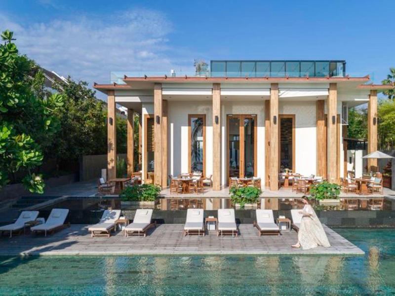 Luxe villa met zwembad, zonneterras en ligstoelen omgeven door groen.