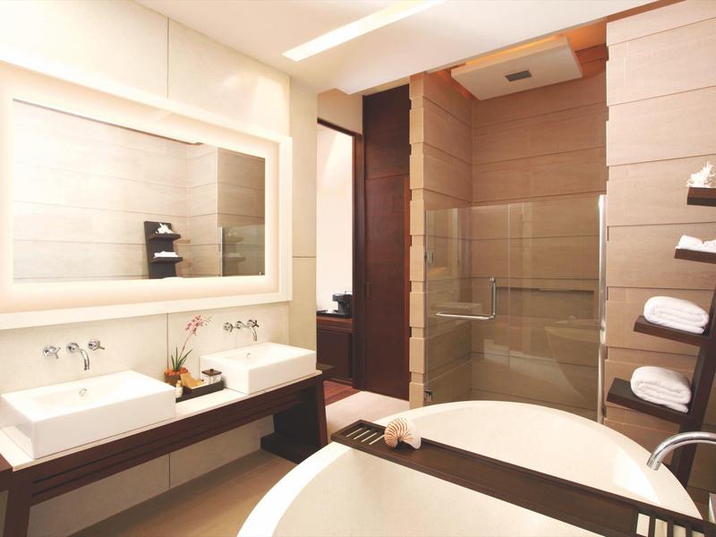 Moderne badkamer met dubbele wastafel, grote spiegel en badkuip met glazen douche.