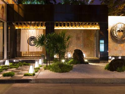 Abendlicher Hotelgarten mit minimalistischer Beleuchtung und Skulpturen.