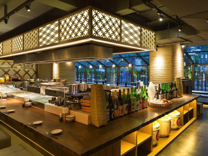 Modernes Restaurant mit langem Holztresen, warmem Licht und klar strukturiertem Interieur.