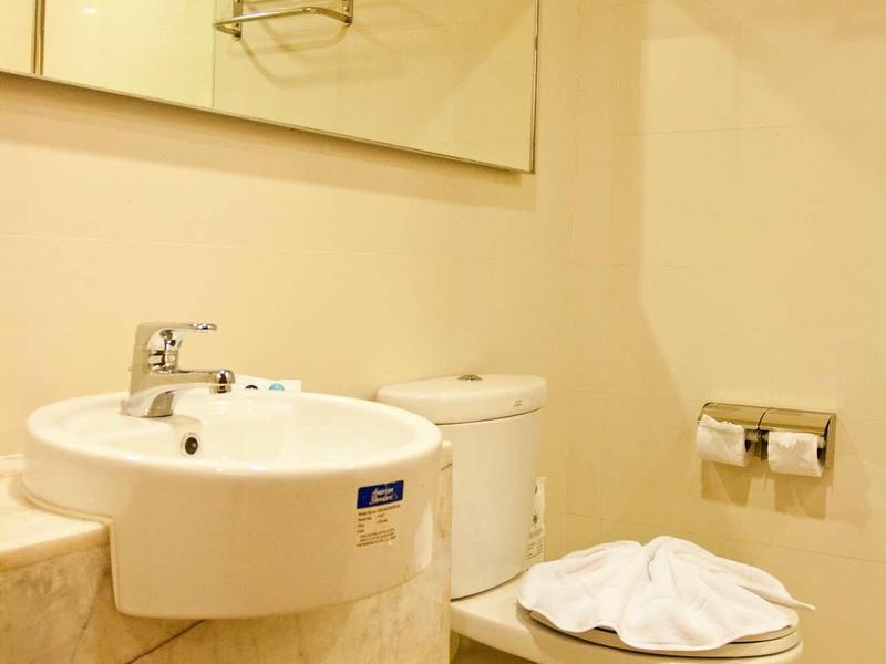 Helles Badezimmer mit Waschbecken, Toilette, großem Spiegel und Toilettenpapierhalter.