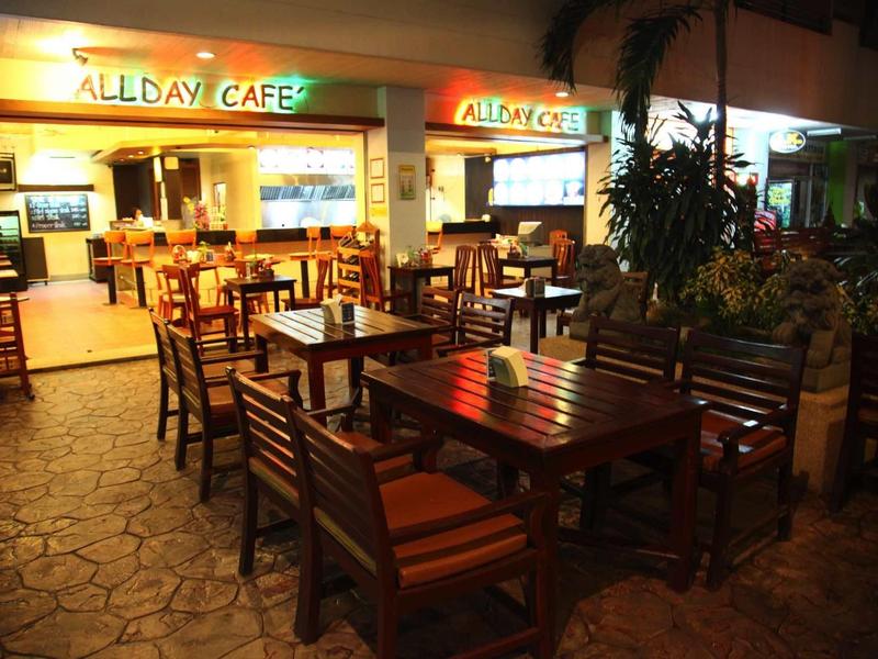 Außenbereich eines Cafés mit Holztischen und Stühlen auf Steinboden bei Nacht.