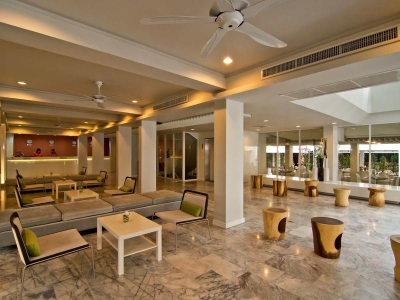 Großer, offener Wohnbereich mit beigen Möbeln, Holzstühlen, Steinboden und Deckenventilatoren.