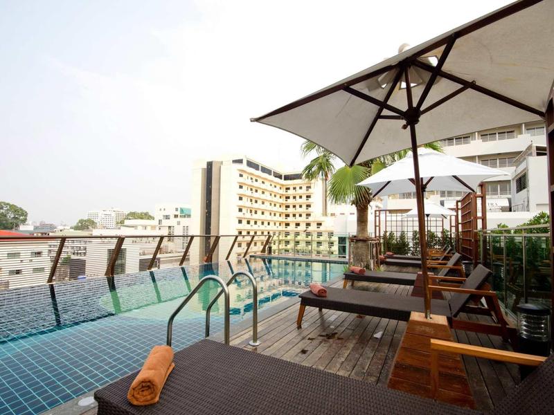 Dachterrassen-Pool mit Liegen, Sonnenschirmen und Blick auf umliegende Gebäude.