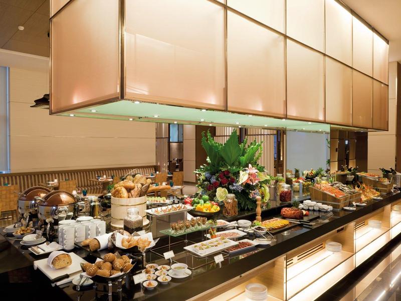 Buffet mit vielfältigen Speisen, Gebäck, Obst und Dekoration auf schwarzer Oberfläche.