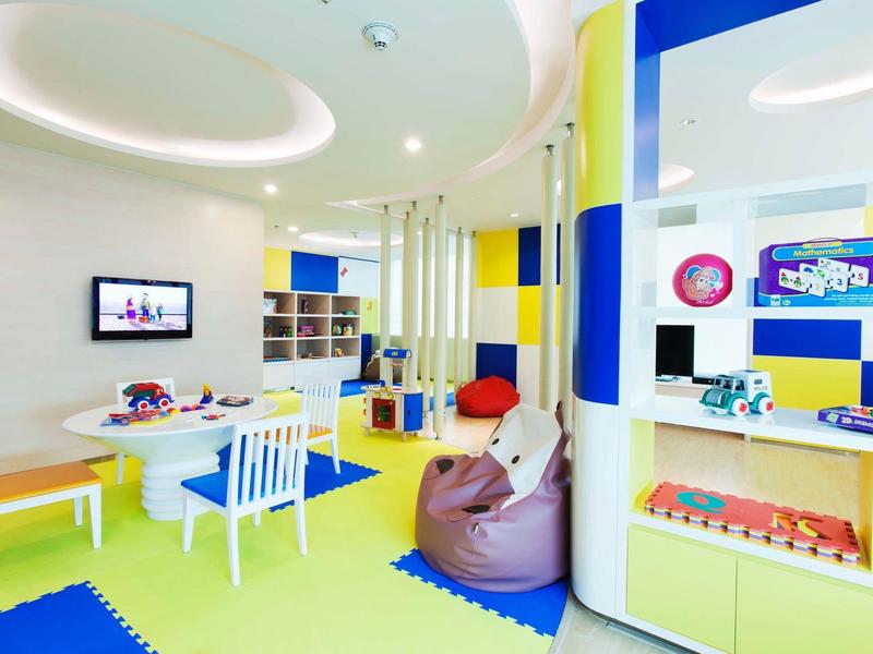 Heller, bunter Kinderraum mit blau-gelben Wänden, Sitzsäcken, Tischen und Spielzeugregalen.