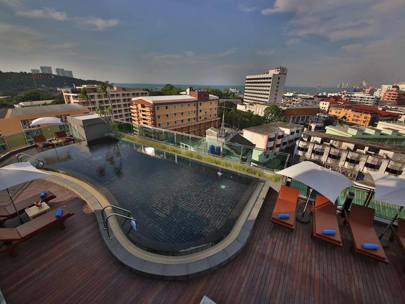 Dachterrasse mit rundem Pool, Sonnenliegen und Stadt im Hintergrund bei klarem Himmel.