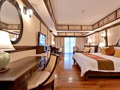 Elegant hotel room with double bed, desk, TV, and balcony with curtains.