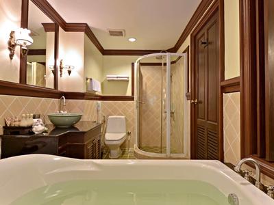 Elegant bathroom with whirlpool tub, vessel sink on wooden vanity, and glass-enclosed shower.