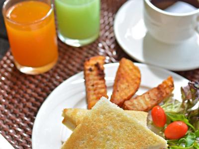 Breakfast with sandwich, orange juice, green juice, and coffee on a wicker placemat.