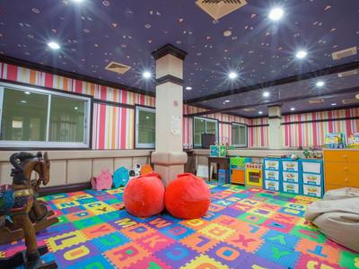 Colorful kids' playroom with mats, toys, and large red balls in a hotel.