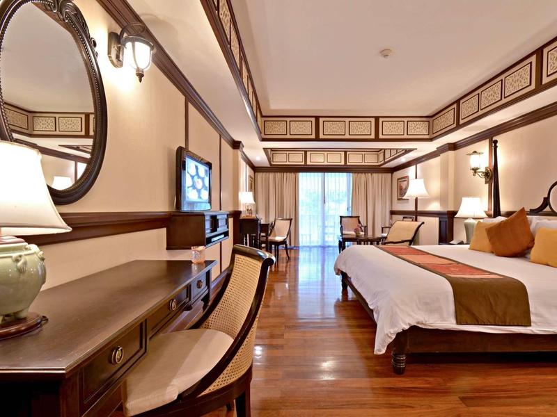 Elegant hotel room with double bed, desk, TV, and balcony with curtains.