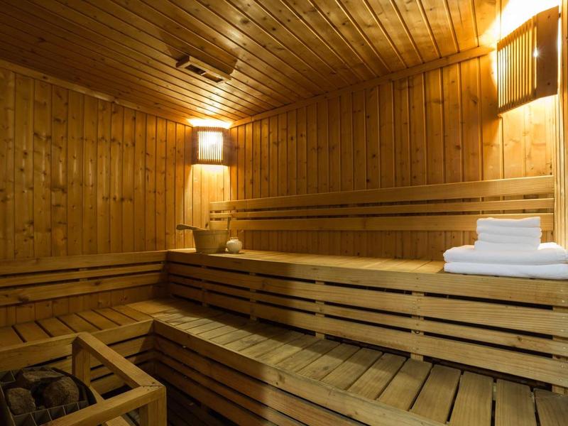 A cozy sauna with wooden paneling, wooden benches, and folded towels.