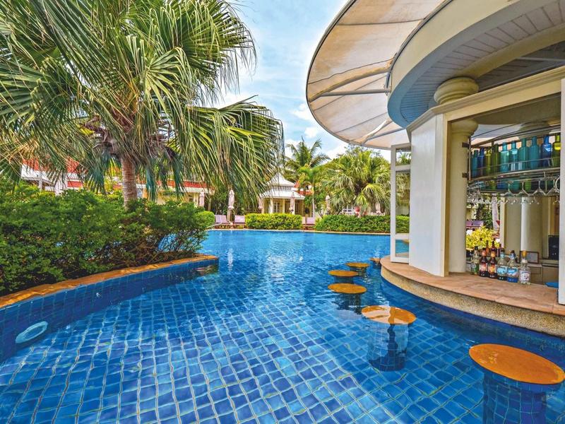 Swim-up bar with stools in the water, surrounded by palm trees and tropical plants.