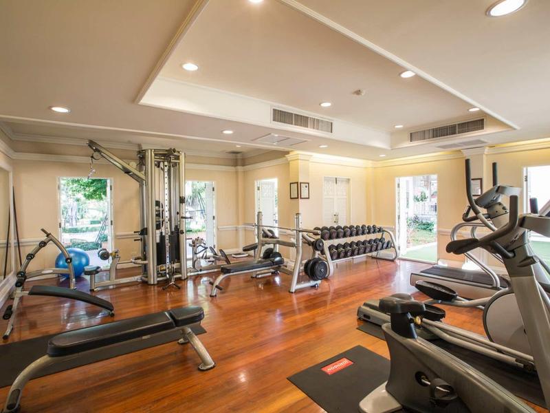Modern gym with dumbbells, treadmill, elliptical, and large windows.