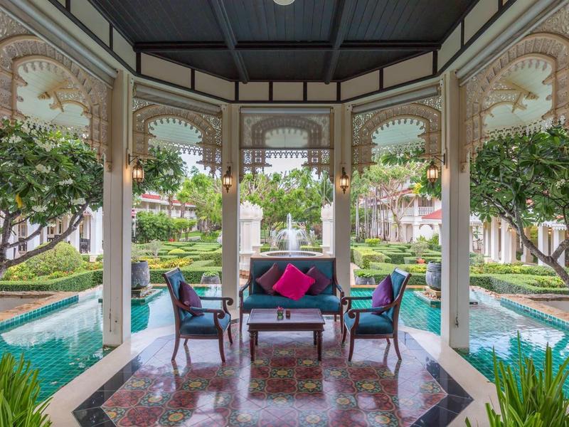 Covered seating area overlooking two water pools, surrounded by lush greenery.