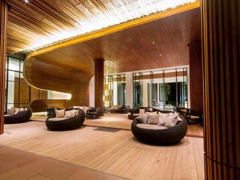 Modernes Loungezimmer mit runden Sesseln, warmen Holztönen und einer geschwungenen Decke.