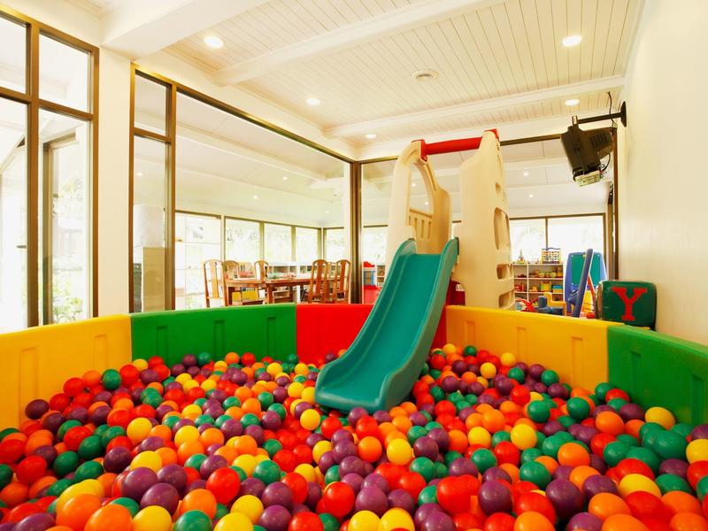 Overdekte speelruimte met kleurrijk ballenbak en glijbaan in een lichte kamer.