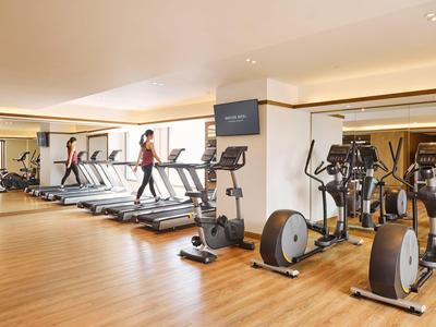 Moderne Fitnessstudio mit Laufbändern, Ellipsentrainern und Holzfußboden in einem Hotel.
