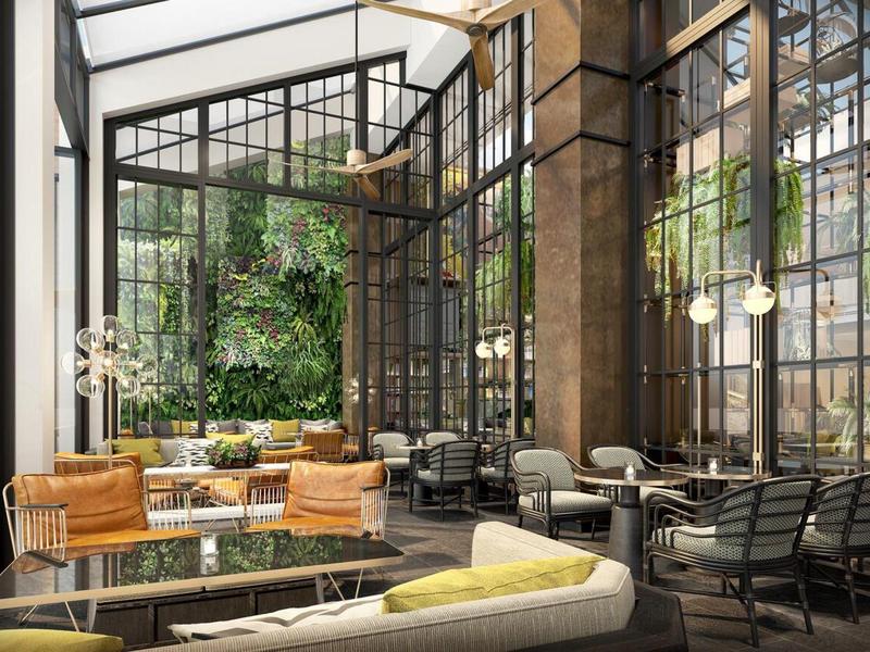 Helles Café mit großen Fenstern, Pflanzenwand, gemütlichen Sofas und modernen Stühlen.