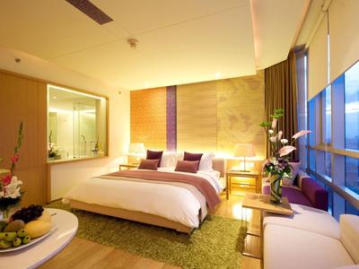 Modernes Hotelzimmer mit großem Bett, beleuchtetem Badebereich und Panoramafenstern.