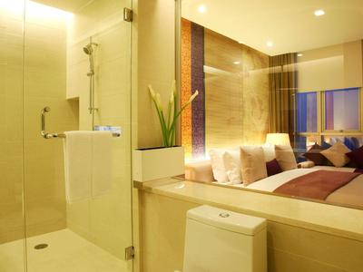 Modernes Hotelzimmer mit Dusche aus Glas, Bett und stilvoller Beleuchtung.