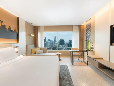 Modernes Hotelzimmer mit großem Bett, Schreibtisch und Blick auf eine Stadtlandschaft.