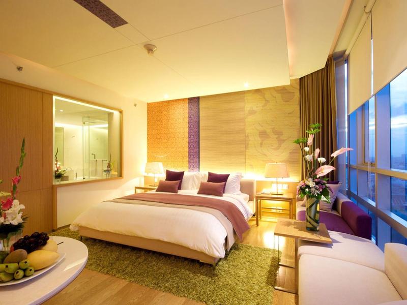 Modernes Hotelzimmer mit großem Bett, beleuchtetem Badebereich und Panoramafenstern.