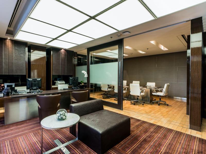 Modern eingerichtetes Hotelbüro mit Sitzbereich und Konferenzraum mit Glastrennung.