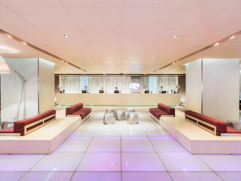 Moderner Hotellobby mit weißen und roten Sitzbänken und beleuchtetem Boden.