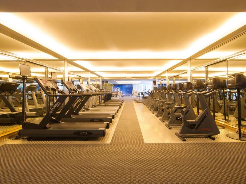 Großer Fitnessraum mit Laufbändern und anderen Trainingsgeräten, hell beleuchtet und modern.