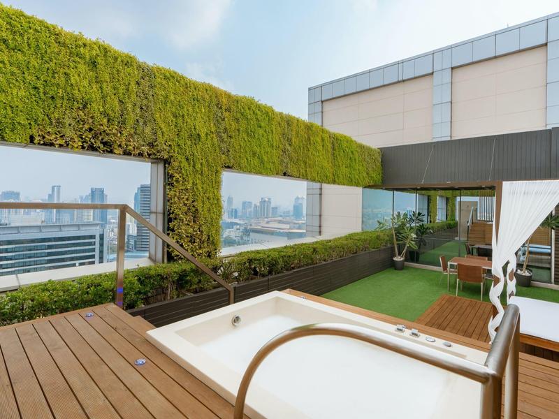 Moderne Dachterrasse mit Whirlpool, Holzdeck und Blick auf eine Stadtansicht.