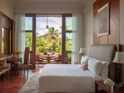 Helles, modernes Schlafzimmer mit großem Bett und Zugang zu einer Terrasse mit tropischem Blick.