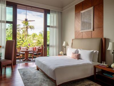 Modernes Hotelzimmer mit großem Bett und Blick auf eine grüne Terrasse mit Esstisch.