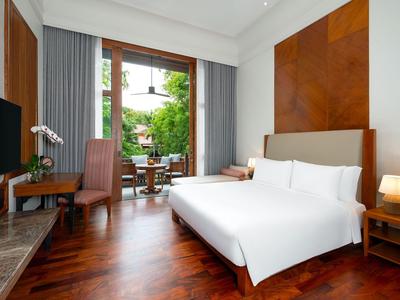 Modernes Hotelzimmer mit großem Bett, Holzfußboden und Blick auf Garten