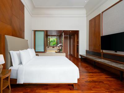 Modernes Hotelzimmer mit großem Bett, Holzfußboden und Flachbildfernseher an der Wand.