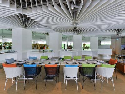 Moderner Speiseraum mit farbigen Stühlen und runder Deckenstruktur in einem Hotel.