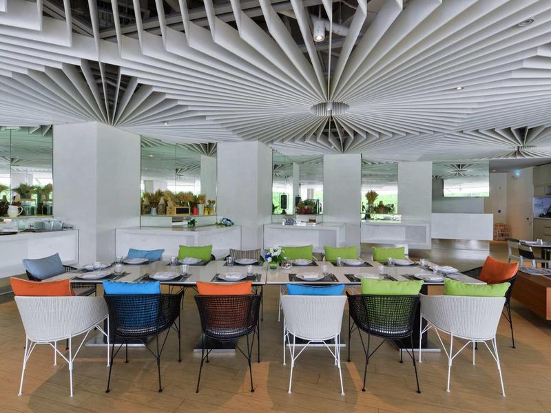 Moderner Speiseraum mit farbigen Stühlen und runder Deckenstruktur in einem Hotel.