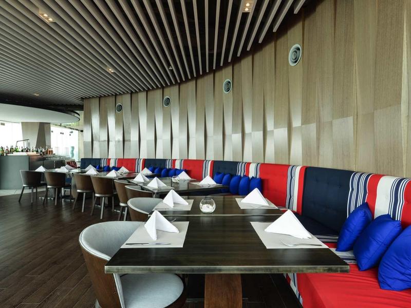 Moderner Restaurantbereich mit bunten Sitzbänken und weißen Tischdecken in einem Hotel.