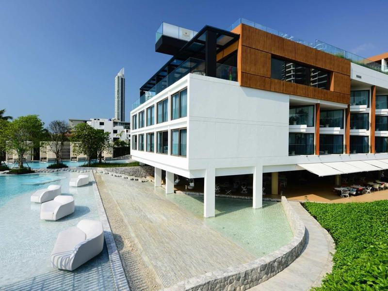 Modernes Hotelgebäude mit Pool und Liegestühlen unter blauem Himmel