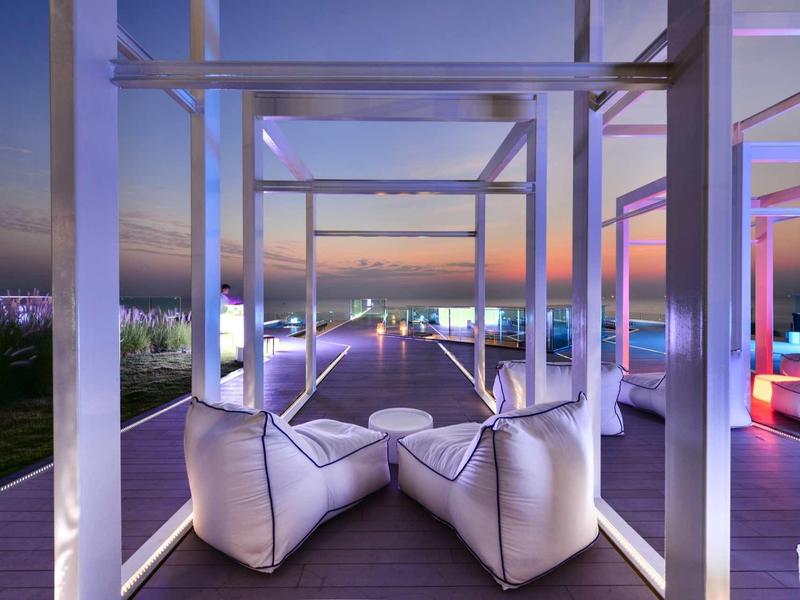 Moderner Außenbereich mit Lounge-Sesseln und spektakulärem Sonnenuntergangsblick über die Stadt.