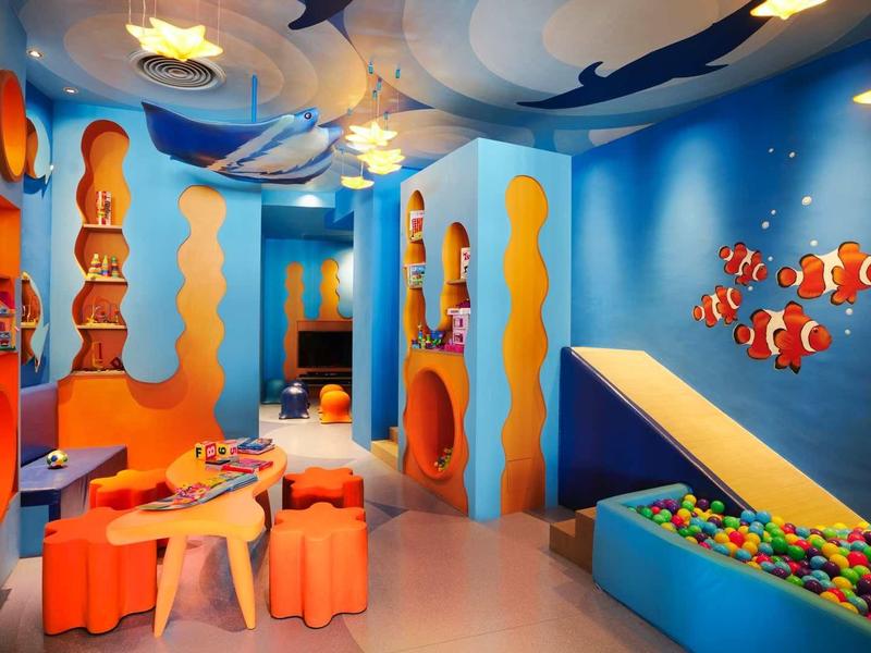 Buntes Kinderzimmer mit Meeresbewohner-Wandmalerei, Bällebad und Spielbereich in Blau und Orange.