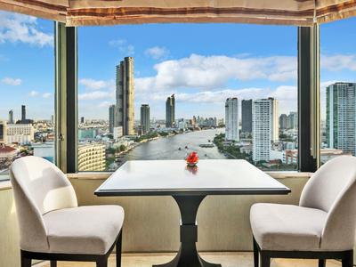 Moderner Essbereich mit Tisch, zwei weißen Stühlen und großer Fensterfront, Blick auf Stadt und Fluss.