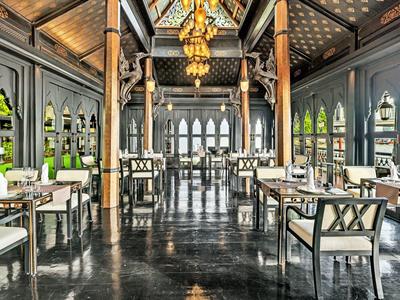 Großer, eleganter Speisesaal mit hohen Decken, dunklem Boden, goldenen Lampen und modernen Stühlen.