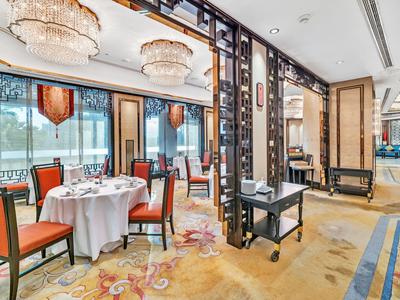 Eleganter, heller Speisesaal mit dekorativen Kronleuchtern und Tisch mit orangenen Stühlen im Hotel.