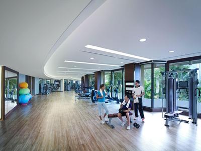 Moderner Fitnessraum mit Holzfußboden, Geräten und großen Fenstern mit Blick ins Grüne.