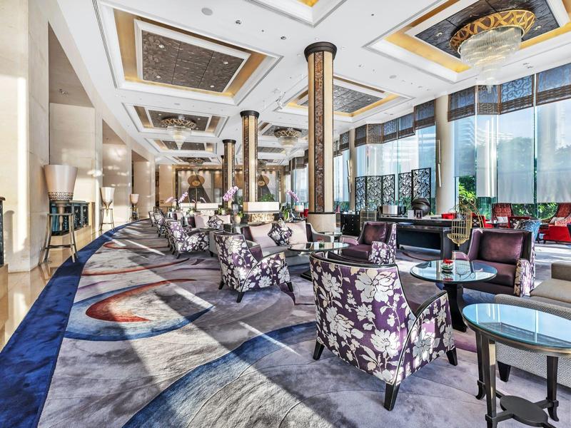 Großer, moderner Loungebereich mit bunten Sesseln, eleganten Säulen und großen Fenstern.