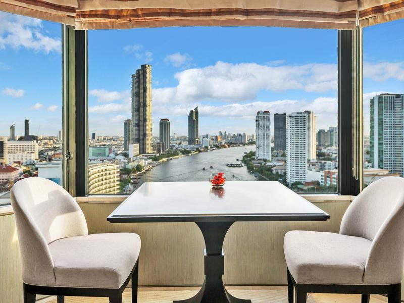 Moderner Essbereich mit Tisch, zwei weißen Stühlen und großer Fensterfront, Blick auf Stadt und Fluss.