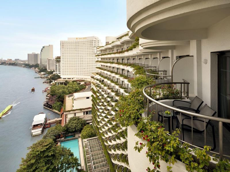 Balkon mit Stühlen und Blick auf Fluss und hoch aufragende Gebäude in einer Stadt.
